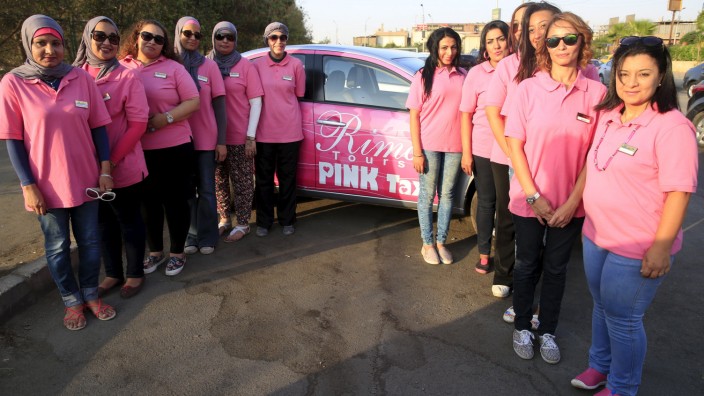 Female drivers of the Pink Taxi company stand in front of a taxi from the company in Cairo, Egypt