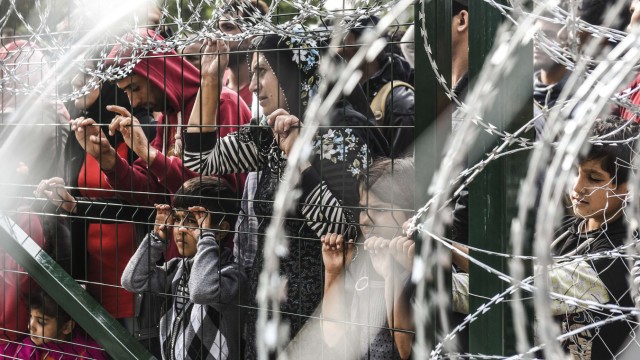 Flucht über den Balkan: Trauriger Blick auf die andere Seite: Flüchtlinge harren an Ungarns Grenzzaun zu Serbien.