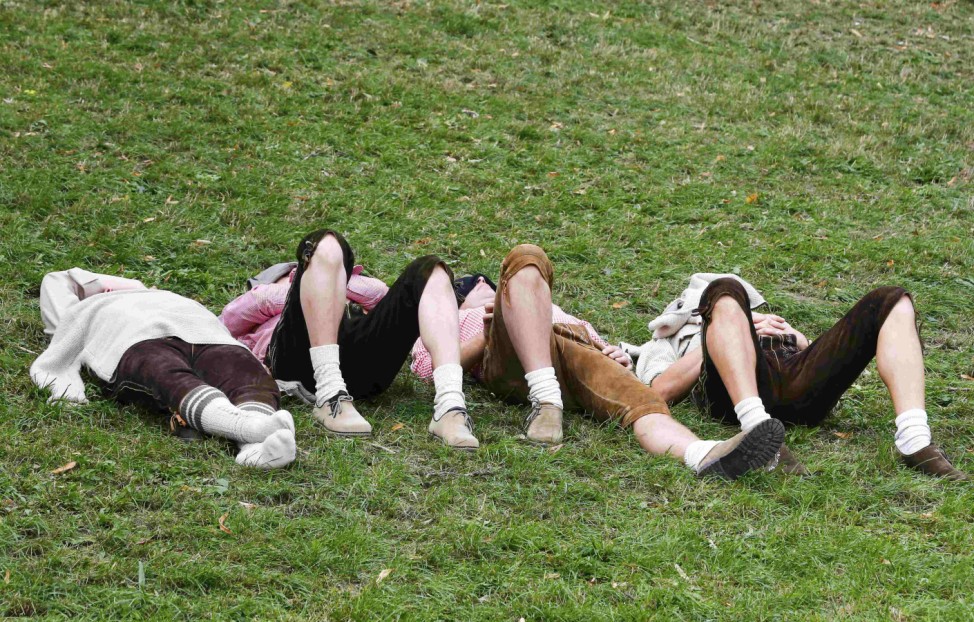 Visitors rest on the grass during the first day of the 182nd Oktoberfest in Munich