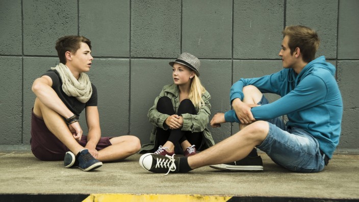 Three teenage friends sitting outdoors model released Symbolfoto PUBLICATIONxINxGERxSUIxAUTxHUNxONLY