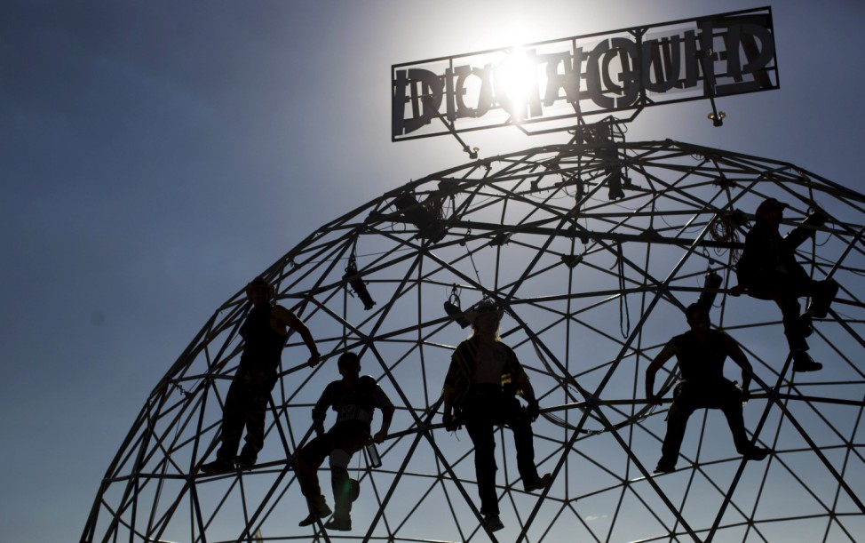 People climb on the Thunderdome as they watch a performance during the Wasteland Weekend event in California City
