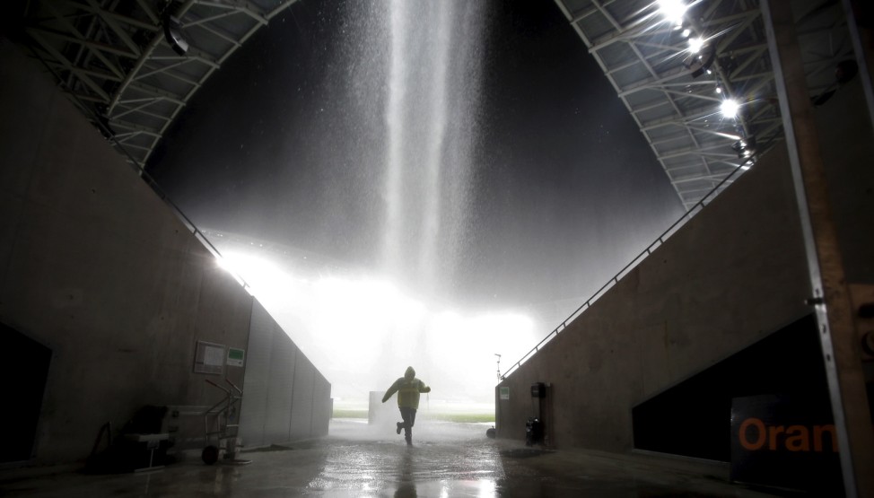 A man runs to protect himself from heavy rain as the French Ligue 1 soccer match between Nice and Nantes is stopped at Allianz Riviera stadium in Nice