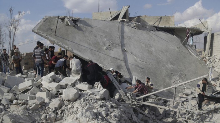 Civil defence members and civilians search for survivors under the rubble of a site hit by what activists said were cluster bombs dropped by Russian air force in Maasran town, south of Idlib, Syria