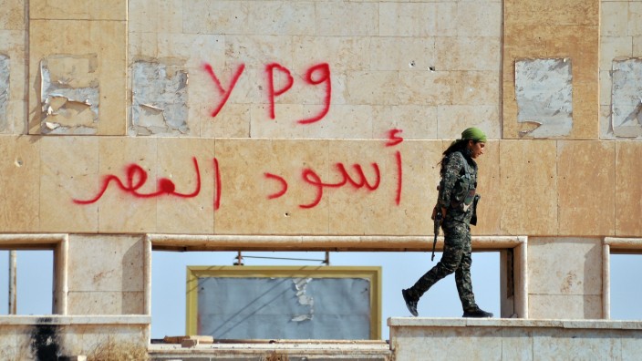 Bürgerkrieg: Jetzt Teil eines Militärbündnisses: Eine Kämpferin der kurdischen Volksschutzeinheiten (YPG) vor einem Graffito im nordsyrischen Al-Hasakeh (Hesîçe), 2. August 2015.