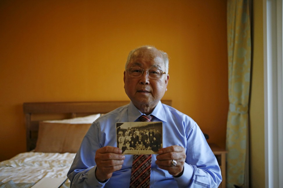 Park Jong-hwan who is selected as a participant for a reunion, poses for a photograph with an old picture at a hotel used as a waiting place in Sokcho