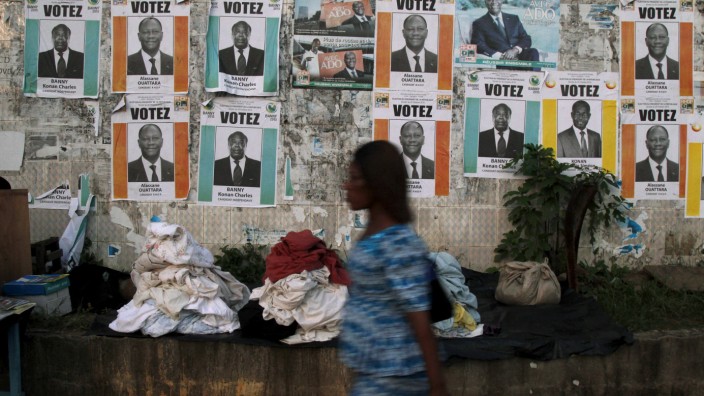 Woman walks past campaign posters ahead of the October 25 presidential election, in Abidjan