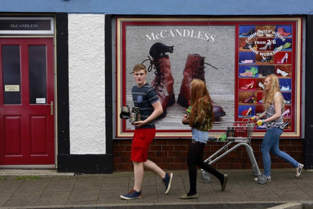 Youths walk past a shop, which has been covered with artwork to make it look more appealing, in the village of Bushmills on the Causeway Coast