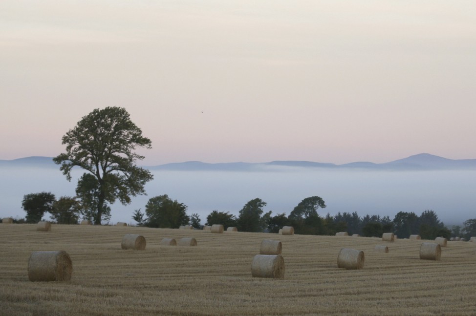 Straw bails are seen in a field on a misty autumn morning near Glamis in Angus, Scotland