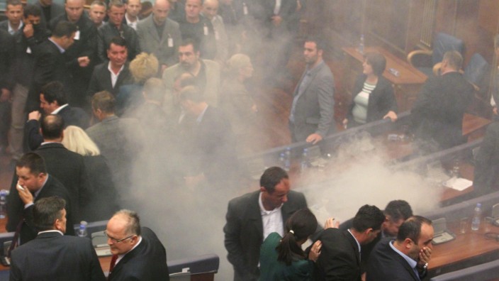 Lawmakers react after opposition politicians release tear gas in parliament in Pristina