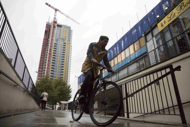 A man rides his bike past a view of the Elephant Park building development in Elephant and Castle south London, Britain