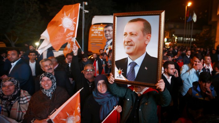 People wave flags and hold a portrait of Turkish President Tayyip Erdogan outside the AK Party headquarters in Istanbul