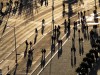 People cast long shadows as they walk along a street during warm and sunny weather in Berlin