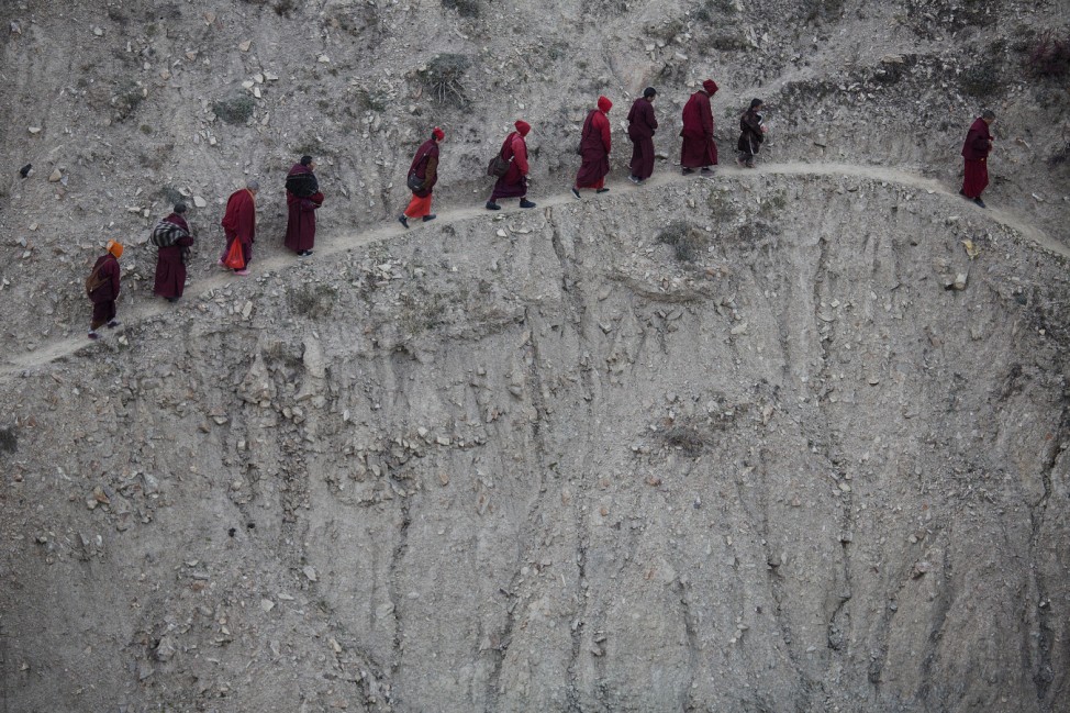 Monks and nuns walk across a steep hill back to their dormitory after attending a daily chanting session during the Utmost Bliss Dharma Assembly at Larung Wuming Buddhist Institute in remote Sertar county