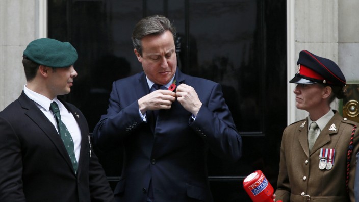 Britain's Prime Minister David Cameron attaches a poppy to his jacket to mark this year's Poppy Appeal at Number 10 Downing Street in central London