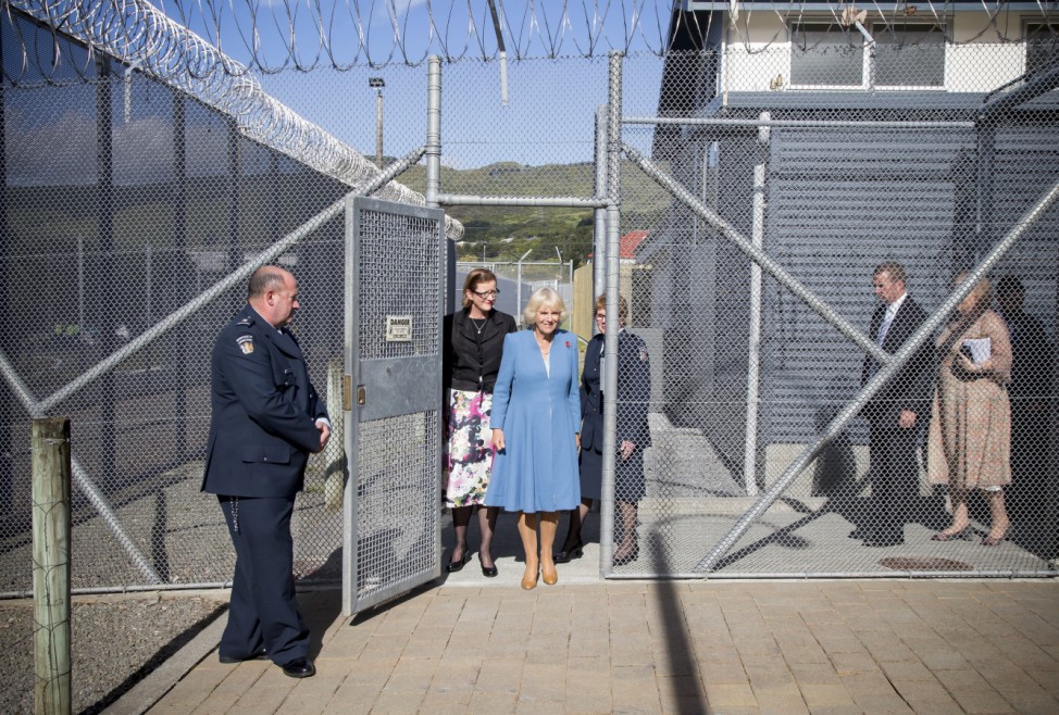 Camilla, Duchess of Cornwall steps through a gate on a high security fence during her visit to Arohata Women's Prison in Wellington, New Zealand