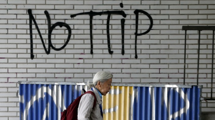Pedestrian walks past graffiti that reads, 'No TTIP', in Brussels, Belgium