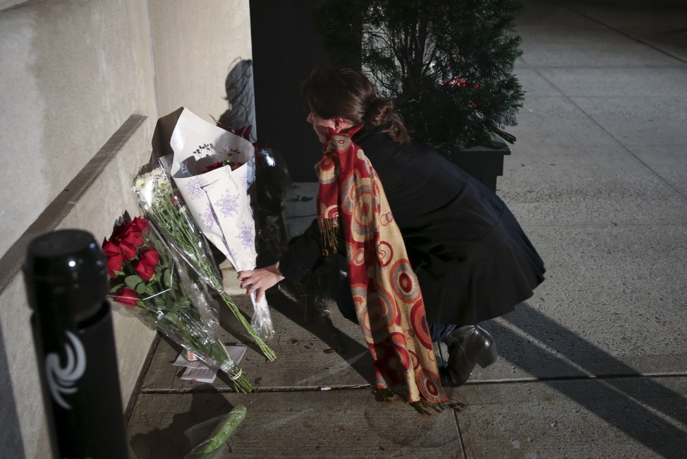 A woman leaves flowers at a small makeshift memorial outside the consulate of France following the attacks in Paris, in the Manhattan borough of New York