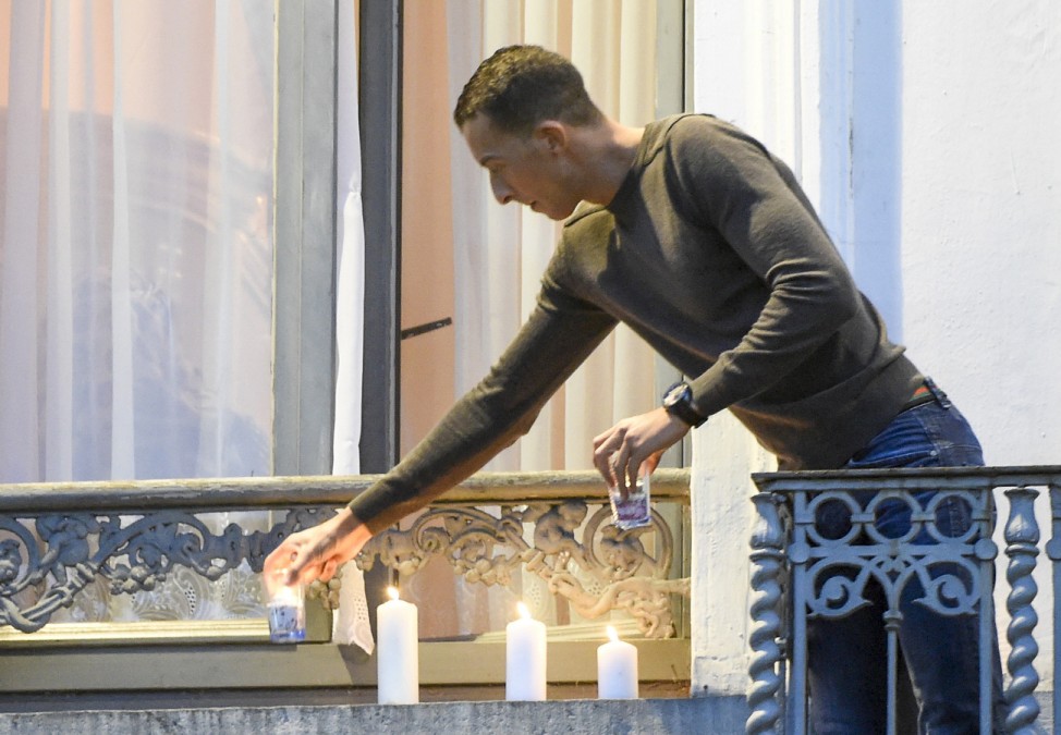 Mohamed Abdeslam, brother of Ibrahim Abdeslam, places candles on the balcony of his house in the Brussels suburb of Molenbeek during a memorial gathering to honour the victims of the recent deadly Paris attacks