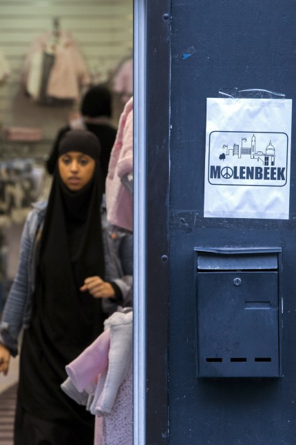 A placard reading Molenbeek with a 'peace and love sign' is seen in a shopping street in the suburb of Molenbeek