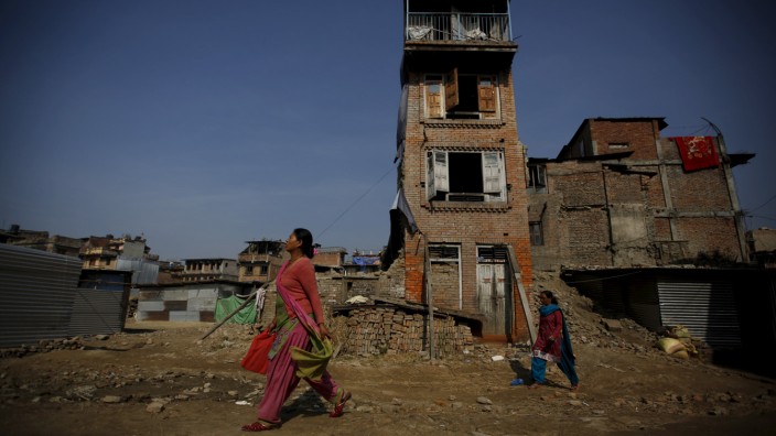 Women walk past houses that were damaged by an earthquake earlier this year, in Bhaktapur, Nepal