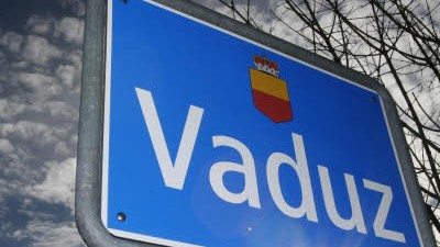 Banken werden nervös: Ortsschild von Vaduz: Dunkle Wolken über dem Finanzplatz Liechtenstein.