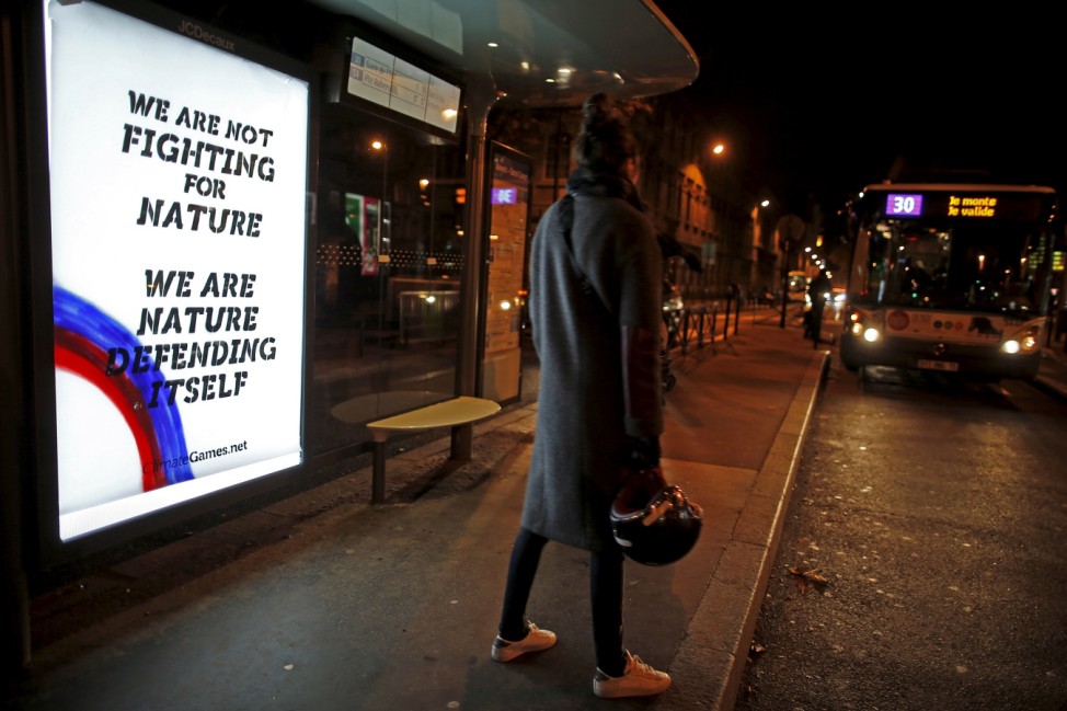A poster by street artist Climate Games as part of the 'Brandalism' project is displayed at a bus stop in Paris