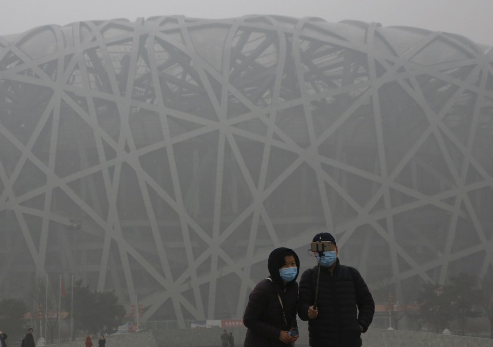 Visitors wearing protective masks take a selfie in front of the National Stadium in Beijing