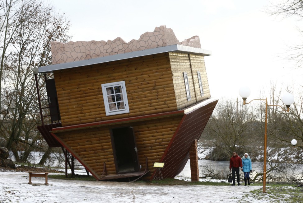 People walk outside an upside-down house in a tourist complex, near the village of Dukora
