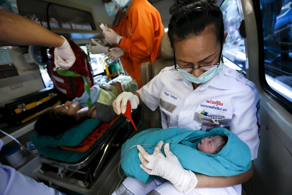 A rescue worker holds a baby after her mother delivered the child in the car that was stuck in traffic in Bangkok