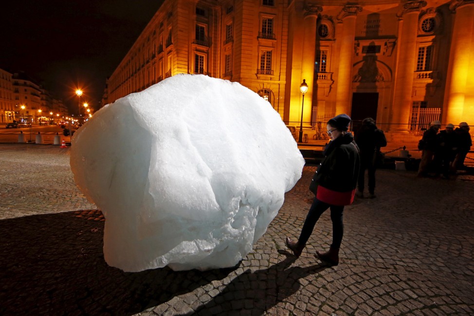 A woman looks at a mass of ice harvested from Greenland during an installation on Place du Pantheon for a project called Ice Watch Paris