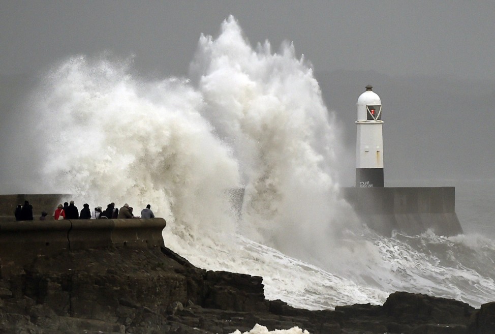 A man and a child stand on the harbour wall during stormy conditions at Porthcawl