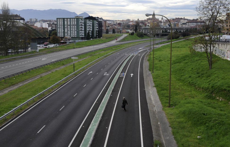 A man walks across the empty A-66 motorway, closed to traffic near the city entrance after the local government took the measure as a bid to curb high levels of pollution, in Oviedo