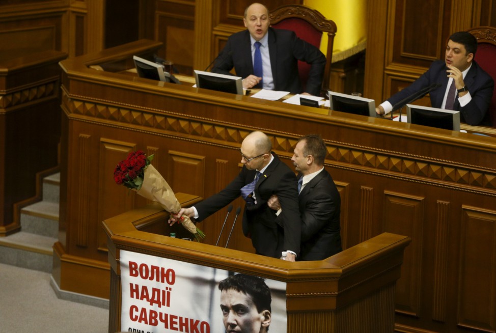 Rada deputy Barna tries to remove PM Yatseniuk from the tribune, after presenting him a bouquet of roses, during the parliament session in Kiev