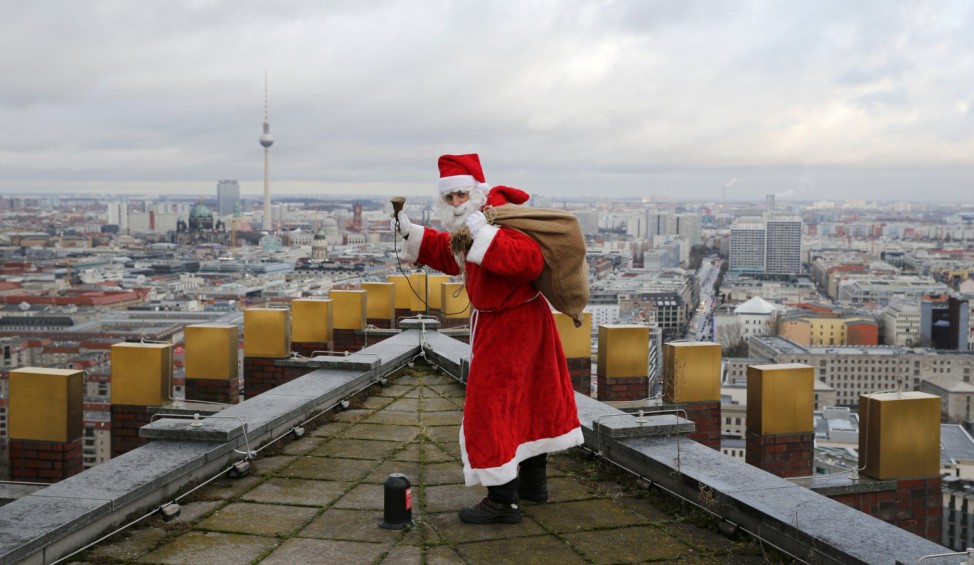 A man dressed as a Santa Claus poses on top of the Kollhoff Tower at Potsdamer Platz square in Berlin
