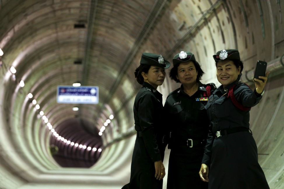 Policewomen take a picture inside a tunnel under the Chao Phraya river at a Mass Rapid Transit subway station in Bangkok