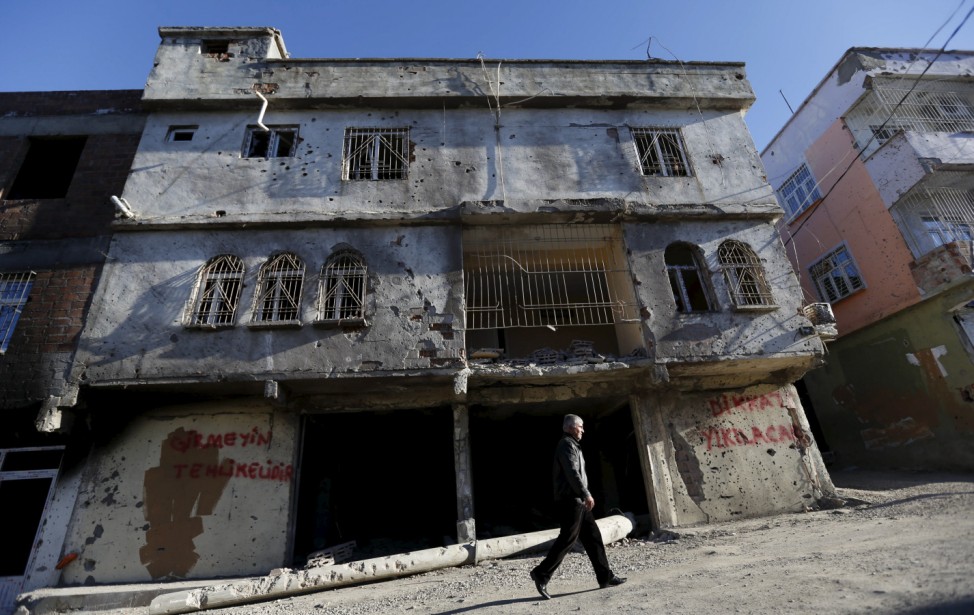 A man walks past a building which was damaged during the security operations and clashes between Turkish security forces and Kurdish militants, in the southeastern town of Silvan in Diyarbakir province, Turkey
