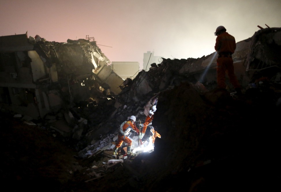Firefighters use flashlights to search for survivors among the debris of collapsed buildings after a landslide hit an industrial park in Shenzhen