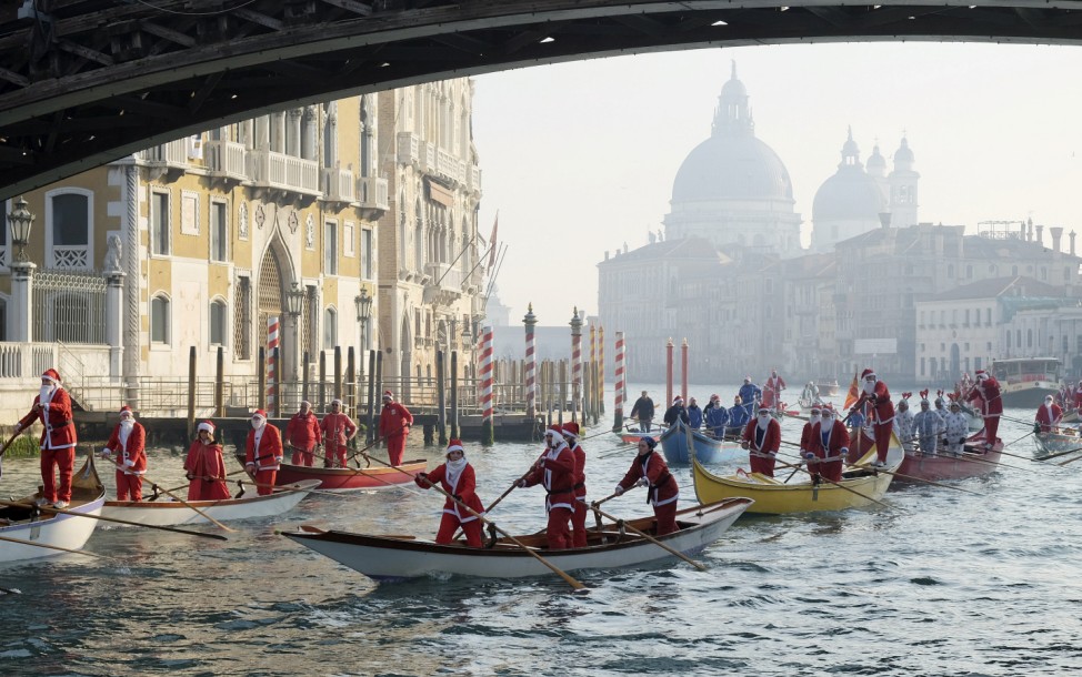 People dressed as Santa Claus row boats on Venice's Grand Canal, in northern Italy