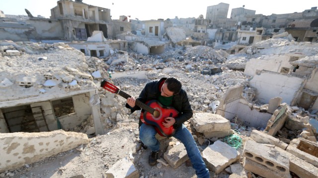 Flüchtlingskrise: Lichtblick: Ein junger Syrer spielt in den Trümmern von Aleppo Gitarre. Musik, findet er, ist der Schlüssel zur Hoffnung.