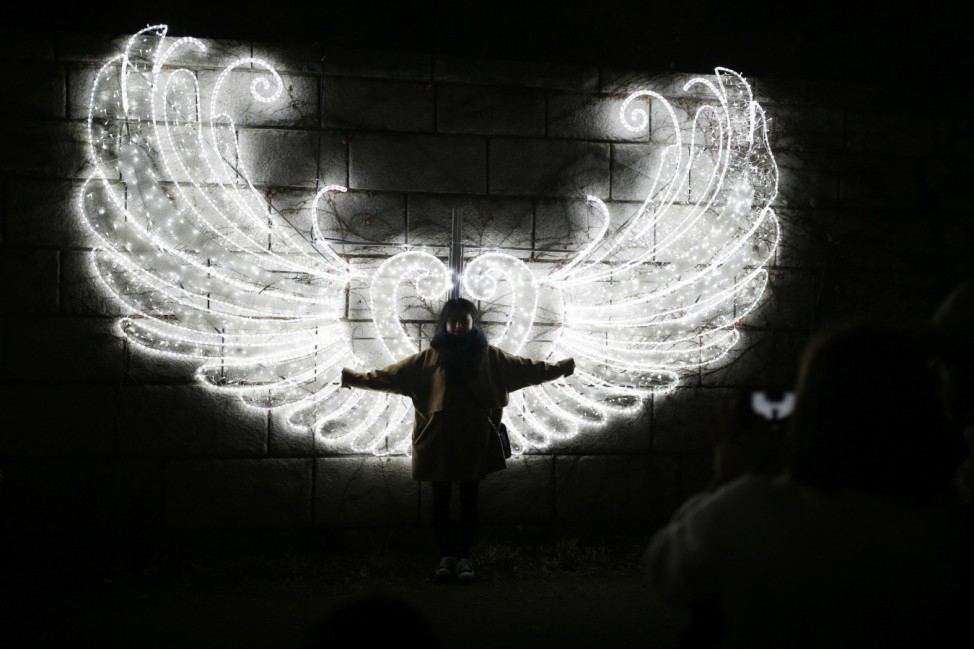 A woman poses for a picture in front of a Christmas illumination at the Cheonggye stream in central Seoul