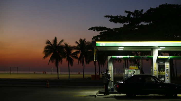 A worker prepares to fill a car at a gas station close to Copacabana beach in Rio de Janeiro