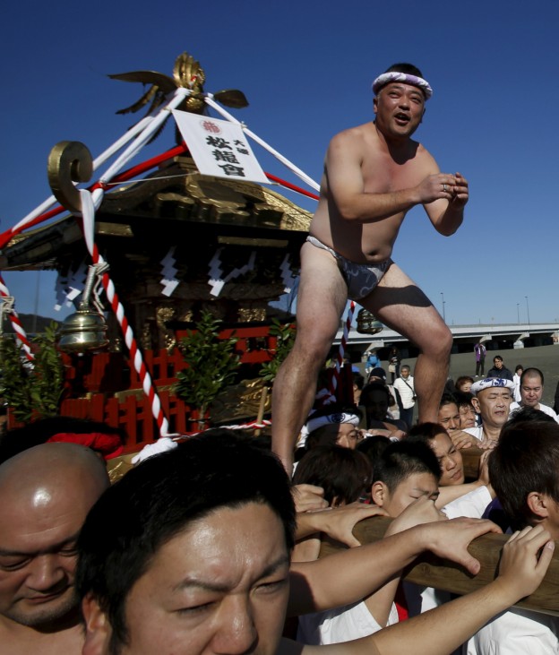 Man wearing the traditional 'fundoshi' or loincloth rides on a 'mikoshi' or portable shrine as local people carry it into the sea during a festival to wish for calm waters in the ocean and good fortune in the new year in Oiso