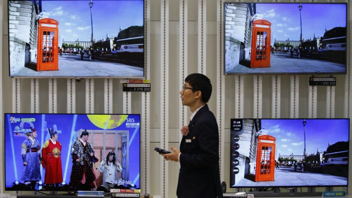 An employee uses his mobile phone in front of LG Electronics' organic light-emitting diode TV sets, which are made with LG Display flat screens, at its store in Seoul