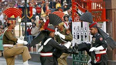 Indisch-pakistanischer Grenzkonflikt: Pakistanische Ehrengarden in schwarzen Uniformen und indische Soldaten (hinten) bemühen sich, am Grenzübergang Wagah Stärke zu demonstrieren.