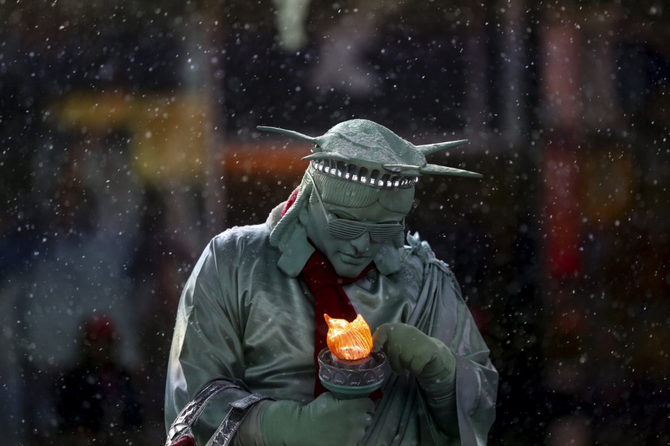 A man dressed as the 'Statue of Liberty' tries to fix his light as it begins to snow in Times Square in the Manhattan borough of New York