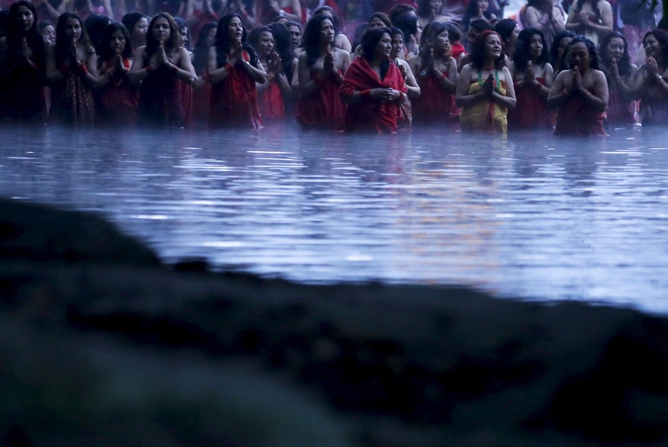 Devotees offer prayers as they submerge themselves in the river before taking a holy bath at Saali River in Sankhu
