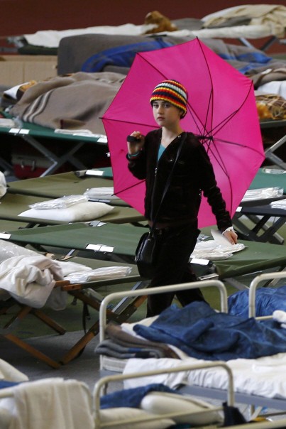 A migrant child carries an umbrella at an improvised temporary shelter in a sports hall in Hanau