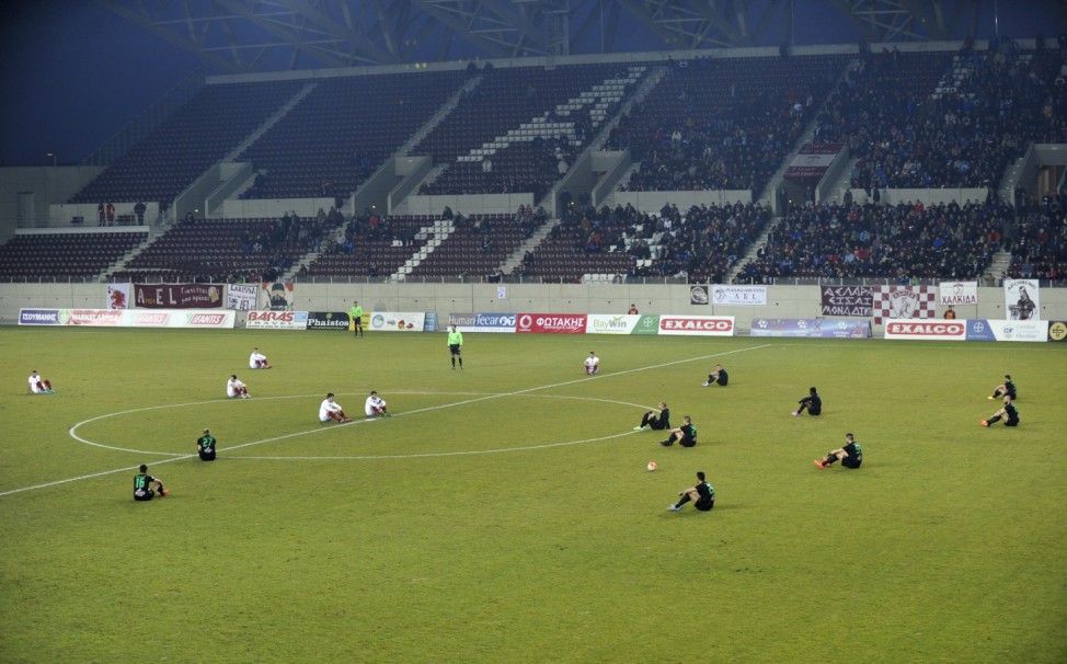 Players of AEL Larissa and Acharnaikos stage a sit-down protest in a tribute to migrants who have lost their lives trying to reach Greece's Aegean islands before the kickoff of their second-tier Football League match in the city of Larisa
