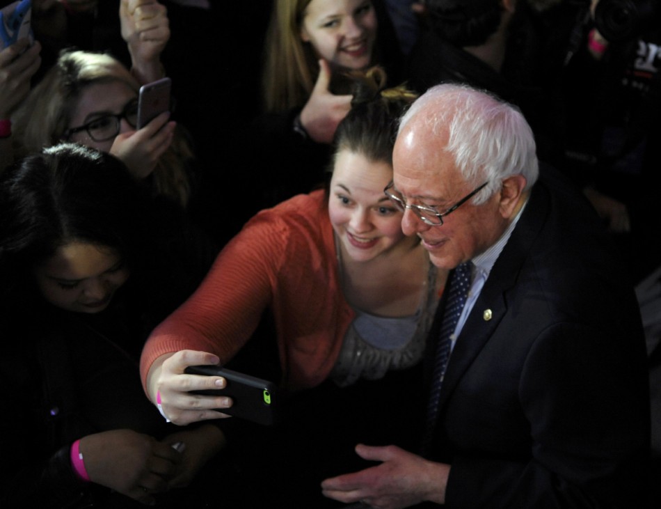 U.S. Democratic presidential candidate Bernie Sanders poses for a selfie with a supporter during his caucus night rally in Des Moines
