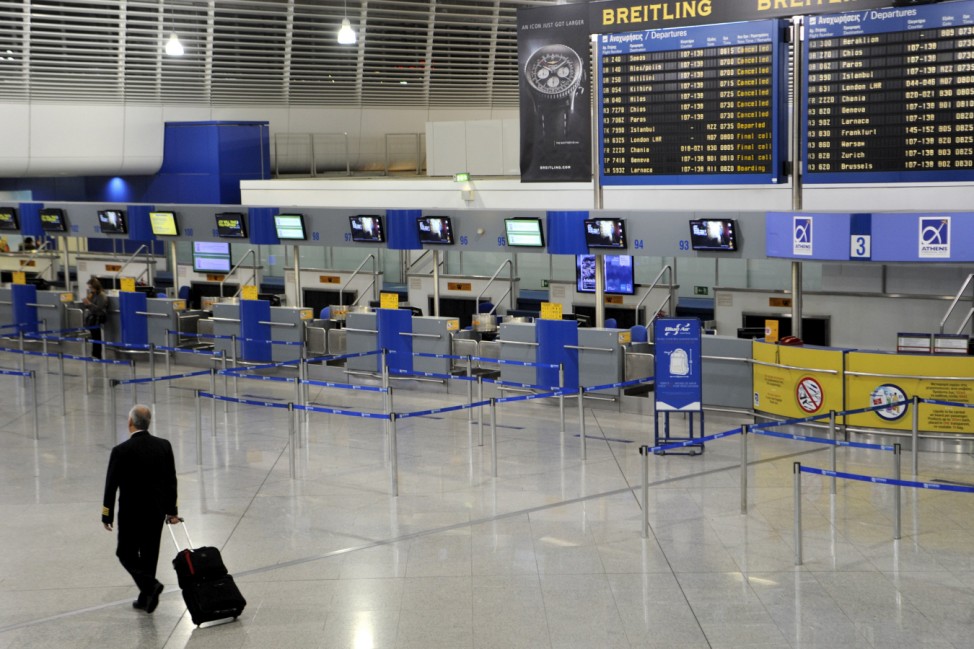 A man makes his way through the empty check-in area of the Athens Eleftherios Venizelos International Airport, as flight controllers hold a work stoppage during a 24-hour general strike against planned pension reforms in Athens